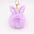 Close-up of fluffy purple bunny ears pompom keychain charm with gold metal clasp detail. - Taro Purple