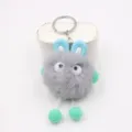 Close-up detail of the cute grey fluffy plush keychain with blue ears and dangling green feet. - Light Gray