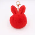 Close up of red plush rabbit ear pompom keychain with gold hardware detail bag pendant. - Dark Red