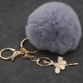 Primer plano de un pompón de felpa gris con un colgante de bailarina de pedrería brillante. - Bailarina - Pelo de conejo Rex sintético / Gris