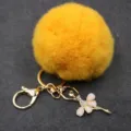 Llavero de pompón de felpa esponjosa amarilla con colgante de bailarina de diamantes. - Bailarina - Pelo de conejo Rex sintético / Naranja