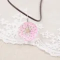 Handmade dried flower necklace featuring a pink floral resin glass ball pendant with cord. - Pink