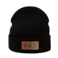 Gedetailleerd overzicht van de zwarte gebreide muts met DAD leren patch voor koude dagen. - Verstelbaar / Zwart
