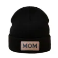 Black knit beanie detail featuring a brown leather patch with MOM text lettering. - Black