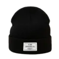 Primer plano de gorro de punto negro con parche de marca blanco, accesorio de invierno cálido. - Talla única / Negro
