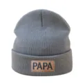 Detalle en primer plano del gorro de punto gris, destacando el parche de cuero marrón. - Gris
