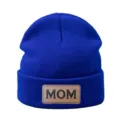 Gros plan détaillé d'un bonnet en tricot bleu roi avec écusson cuir marron texte. - Bleu saphir
