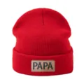 Vista detallada del gorro de punto rojo con un elegante parche de cuero y textura suave. - Rojo