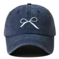 Gros plan sur la délicate broderie de nœud blanc sur la casquette en denim vieilli. - Réglable / Bleu marine