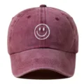 Detalle en primer plano de gorra de béisbol de algodón lavado con cara sonriente bordada blanca. - Ajustable / Burdeos