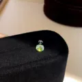 Macro detail view of a sparkling green cubic zirconia round stud earring on a black velvet box. - Single Piece / Yellow-Orange-5mm