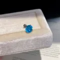 Detailed close-up of a vibrant blue zircon stud earring placed on a soft velvet jewelry box. - Pair / Stud Earrings - Silver & Blue - 7mm