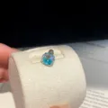 Detailed close-up of a sparkling iridescent zircon threaded stud earring on a beige display. - Single Piece / Blue-Green-7mm