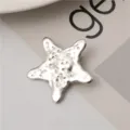 Detailed close-up of a silver metallic starfish hair clip with unique textured design. - Hammered Stars