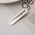 Detailed shot of a sleek silver metal hair clip, minimalist duckbill design, close-up view. - Hollow Round Head Clips