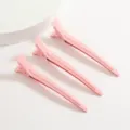 Gros plan de trois pinces à cheveux bec de canard en aluminium rose avec finition laquée. - Rose