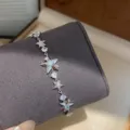 Primer plano detallado de una delicada pulsera plateada con dijes de estrellas. - Plata Con Azul