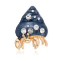 Detailed closeup of exquisite hermit crab shell brooch with blue enamel and sparkling rhinestones. - Blue