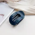 Close-up of dark blue oval hair claw clip on soft fabric background, elegant daily hair styling. - Navy Blue
