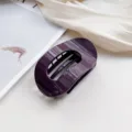 Detail shot of a sleek dark purple oval hair claw clip, elegant minimalist design for secure styling. - Deep purple