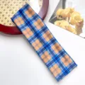 Gedetailleerd uitzicht op de klassieke sporthaarband met ruitjespatroon in blauw en oranje. - Blauw Oranje