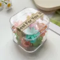Nahaufnahme niedlicher Mini-Blumen-Haarklammern in transparenter Box, bunte Haarspangen für Kinder. - Frühlingsfarbe Frangipani