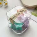 Detailaufnahme einer transparenten Box mit bunten Mini Blumen Haarklammern für Kinder. - Frühlingsfarbe Pflaumenblüte