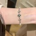 Close-up detail shot of the elegant floral rhinestone and pearl bracelet worn on the wrist. - Bracelet - Silver - Green