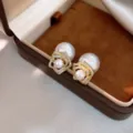 Gros plan détaillé des élégantes boucles d'oreilles perles et zircone fleur dans l'écrin. - Clous Perles Zirconia Plaqué Or 14K (54#) / Or - Perle