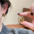 Gros plan détaillé de boucles d'oreilles créoles géométriques minimalistes avec design doré. - Boucles d'oreilles rondes géométriques tendance (31#) / Brun doré