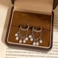 Primer plano de elegantes pendientes de clip de perlas en media luna con joyero vintage. - Cuffs para oreja / Plateado