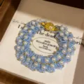 Vista detallada de pulsera de cuentas azul claro hecha a mano con cierre dorado en caja. - Pulsera-Azul Cielo