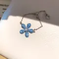 Zilverkleurige verstelbare ring met sprankelend blauw kristallen bloemmotief en kettinkje. - 5# Aquamarijn Verstelbare Ketting Ring / Zilver