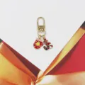 Detailed close-up shot of the cute Christmas bell and candy cane enamel keychain pendant. - Glove Bell And Candy Style (1) / Red & Gold