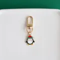 Close-up detail of cute Christmas penguin metal keychain pendant with golden lobster clasp clip. - Penguin