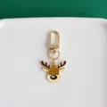 Close-up detail of cute cartoon reindeer keychain, gold metal charm pendant for bags. - Deer
