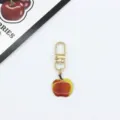 Close-up of the cute apple pendant keychain detail, showing shiny gold clasp and enamel. - Lacquered Apple (6)