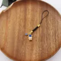 Close-up detail of the golden astronaut phone charm featuring blue star pendant and strap. - Gold Astronaut Style (3)