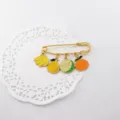 Detalle de un bonito broche de imperdible con colgantes de frutas de esmalte muy colorido. - Colección de Frutas