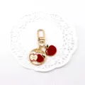 Close-up of a cute gold-tone alloy apple keychain charm with red and white enamel fruit details. - Apple