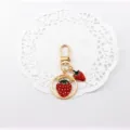 Cute strawberry metal keychain and bag charm, stylish alloy pendant accessory detail shot. - Strawberry