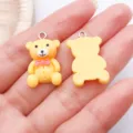 Detailweergave van een schattige gele hars teddybeer bedel met roze strik voor eigen sieraden. - Beer met Strikje (24543) / 1 Stuk (25x15x6.5mm) / Geel