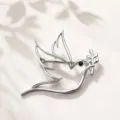 Detailed shot of a minimalist hollow dove bird brooch with olive branch in silver finish. - Silver