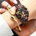 Detailopname van het elegante bloemige kwartshorloge gedragen om de pols met gouden armband. - Stijl 1 (Zwarte Bloemenband met Armband)