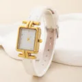 Elegante quadratische Quarzuhr mit weißem Lederarmband und goldenem T-Steg Gehäuse Detail. - Weiß