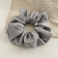 Grijze glanzende stoffen haarelastiek gedetailleerde weergave, elegante getextureerde paardenstaart. - donkergrijs