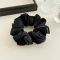 Black satin fabric hair scrunchie detail shot, elegant shiny pony tail holder accessory. - Black