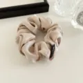 Detail view of a luxurious champagne satin scrunchie with exquisite handmade fabric texture. - Khaki
