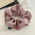 Gedetailleerd overzicht van een elegante glanzende satijnen haarelastiek in mauve met label. - Zoet Roze