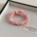 Nahaufnahme eines weichen rosa Satin-Haargummis, der feine Textur und elegantes Design zeigt. - Rosa